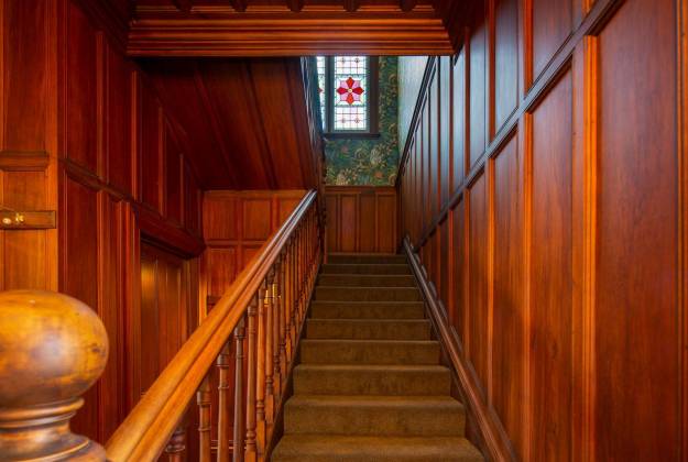 Stairway with wood paneling and stained glass window at The Vicarage Geraldine luxury hotel accommodation